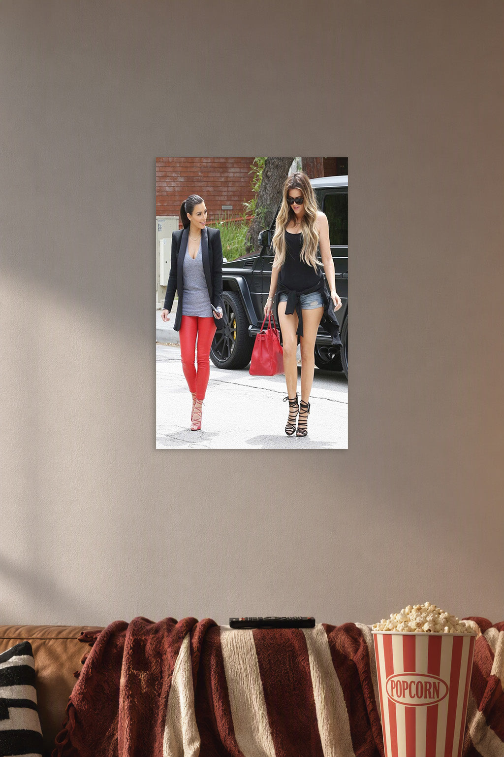 Kim and Khloé Kardashian in a cozy movie room above a brown sofa with popcorn.