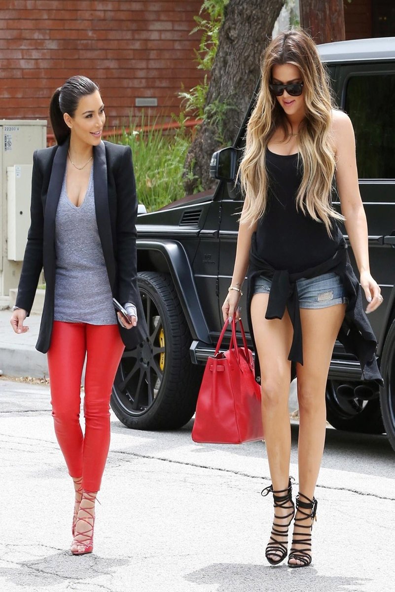 Kim and Khloé Kardashian wall art print featuring the sisters walking beside a black SUV in red pants and denim shorts.