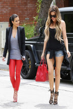 Kim and Khloé Kardashian wall art print featuring the sisters walking beside a black SUV in red pants and denim shorts.