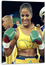 Laila Ali canvas wall art print presents the boxer smiling in yellow gear, holding green gloves up before a dark arena.