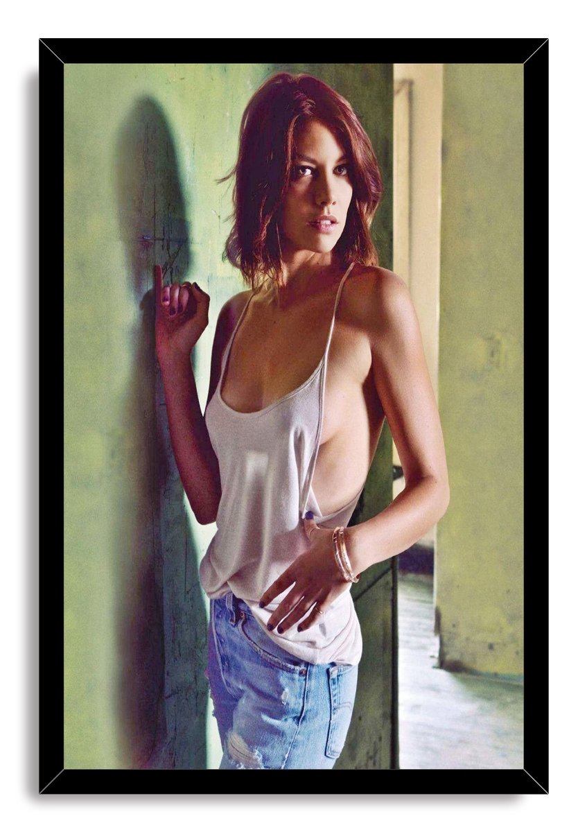 Lauren Cohan framed wall art print depicts a woman in a white tank top and jeans, posed in a softly lit green corridor.