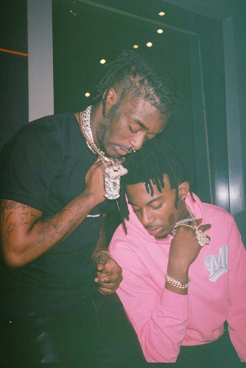 Lil Uzi Vert and Playboi Carti poster features two men looking down in a dark interior, wearing chains and black and pink clothing.