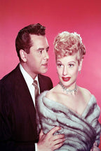 Lucille Ball and Desi Arnaz poster portrait against a pink background, with Ball in a silver fur stole and jeweled necklace.
