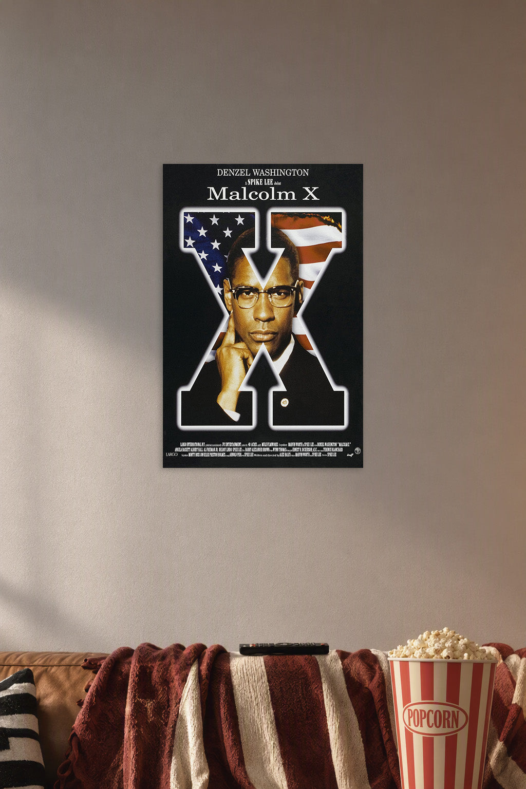 Malcolm X Movie Poster in a cozy movie room above a brown sofa with popcorn.