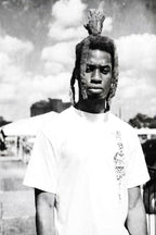 Black-and-white wall art print of a serious man in a white T-shirt, with tall dreadlocks against a cloudy outdoor sky.