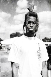 Black-and-white wall art print of a serious man in a white T-shirt, with tall dreadlocks against a cloudy outdoor sky.
