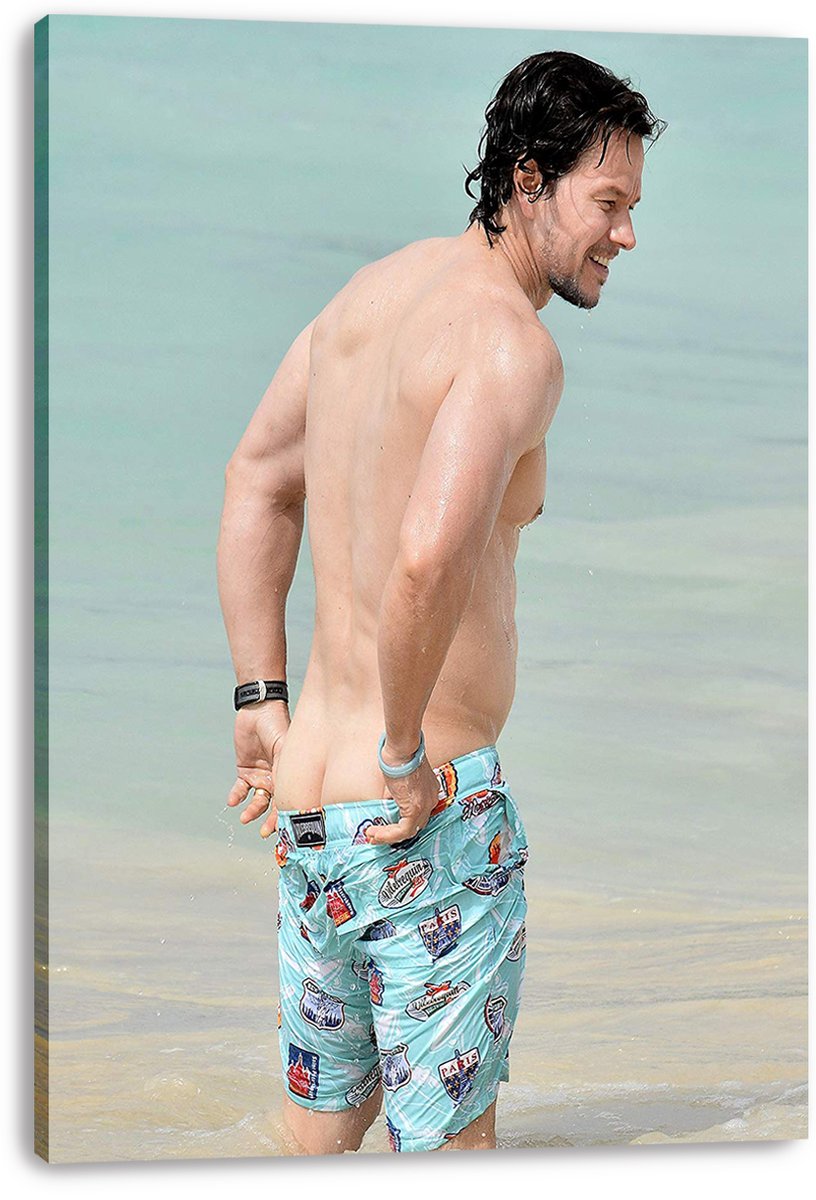 Mark Wahlberg canvas wall art print features the actor standing in pale blue seawater in colorful patterned swim shorts.