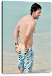 Mark Wahlberg canvas wall art print features the actor standing in pale blue seawater in colorful patterned swim shorts.