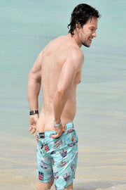 Mark Wahlberg wall art print portrays the actor smiling in shallow turquoise water wearing patterned blue swim shorts.