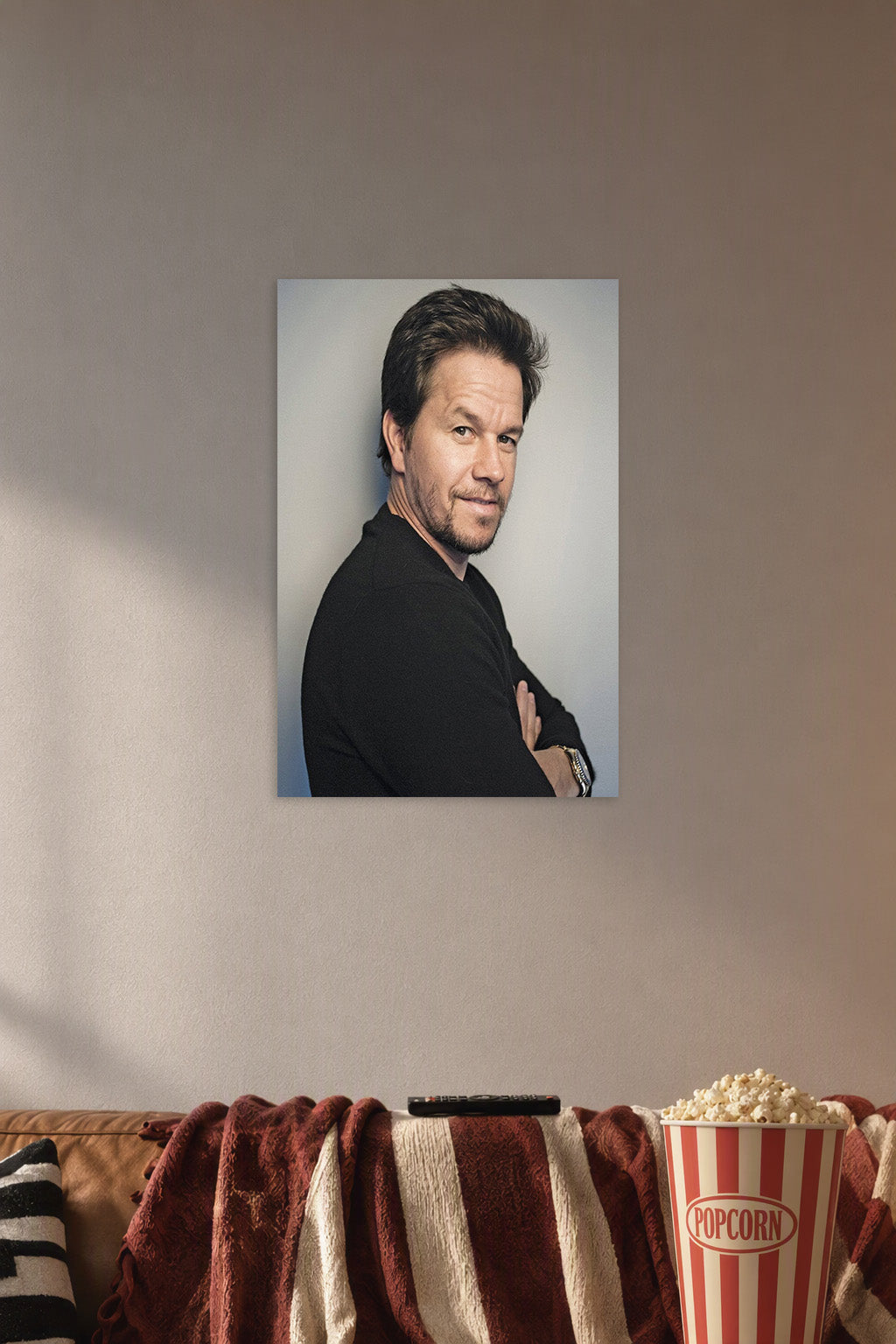 Mark Wahlberg in a cozy movie room above a brown sofa with popcorn.