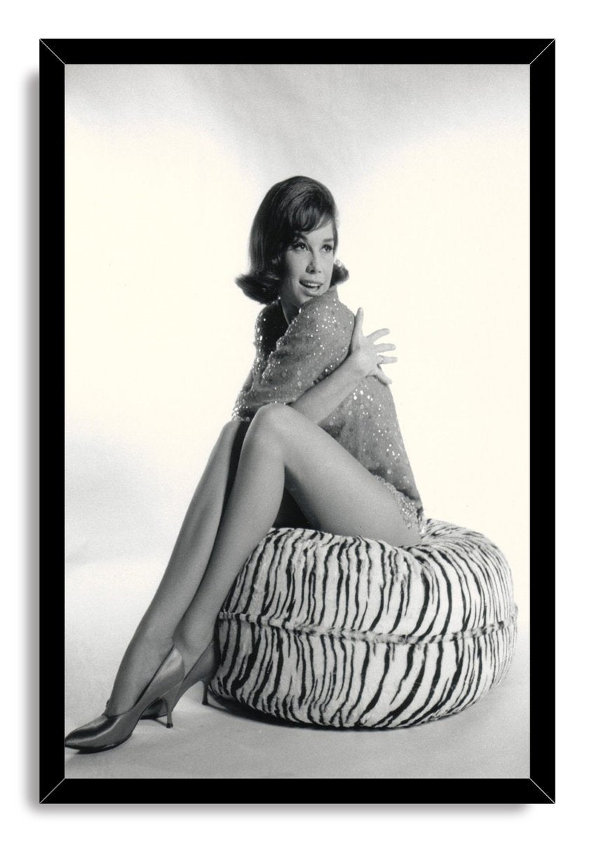 Mary Tyler Moore framed wall art print presents a black-and-white portrait of her posed on a zebra-striped ottoman, bordered in black.