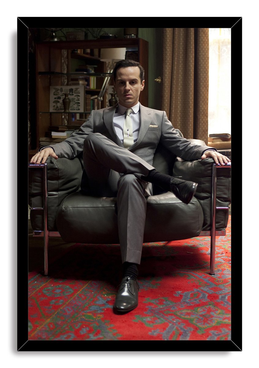 Moriarty framed wall art print portrays Andrew Scott seated cross-legged in a leather armchair, with a black border and red rug.