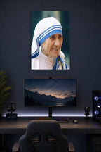Mother Teresa in a gaming desk setup above a monitor.