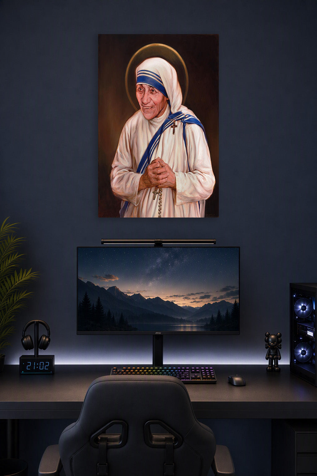 Mother Teresa Saint in a gaming desk setup above a monitor.