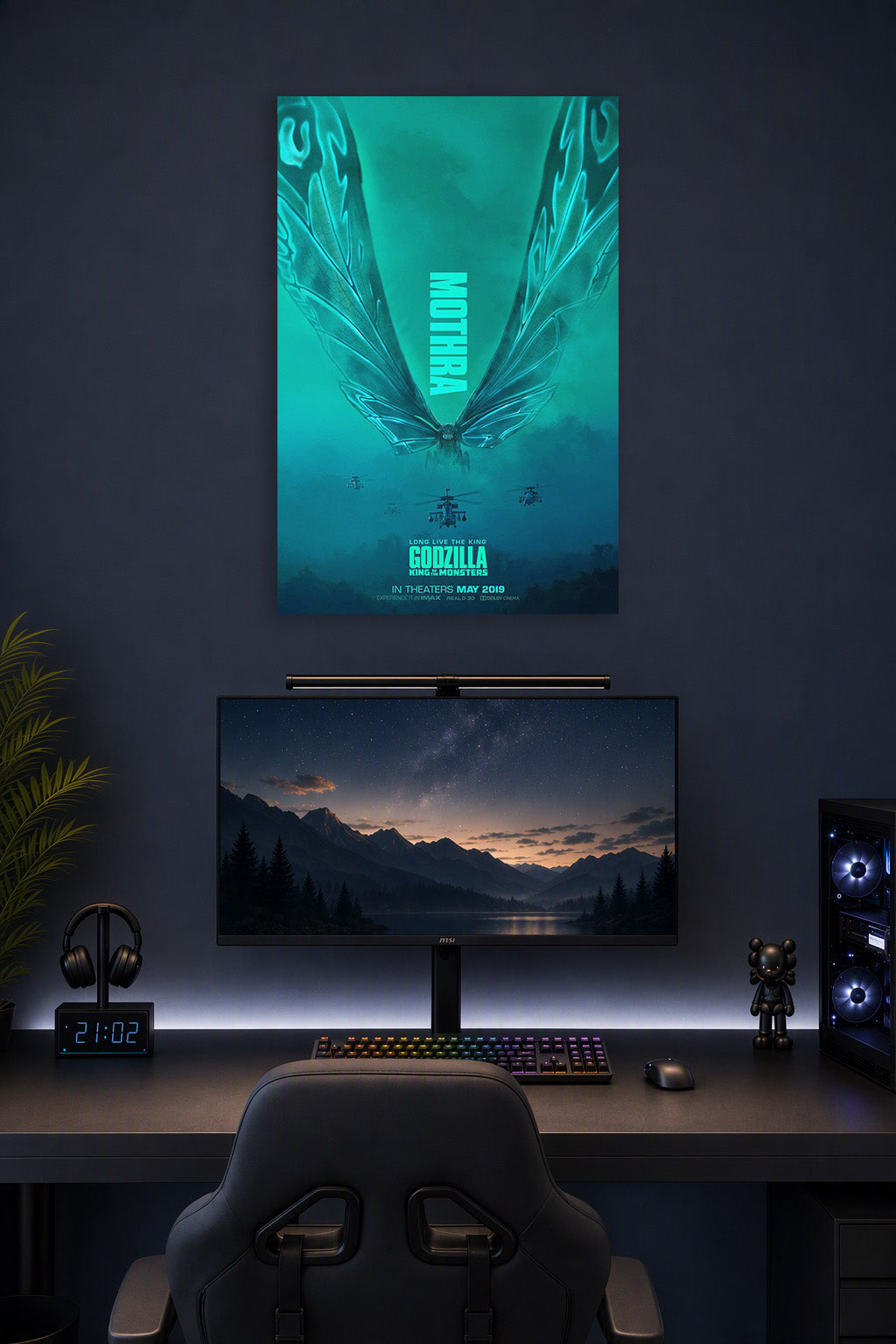 Mothra in a gaming desk setup above a monitor.