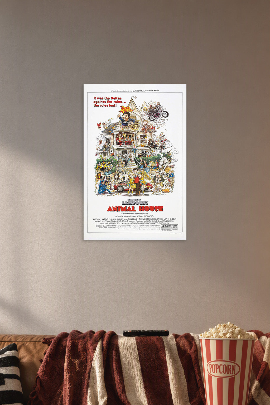 National Lampoon's Animal House Movie in a cozy movie room above a brown sofa with popcorn.