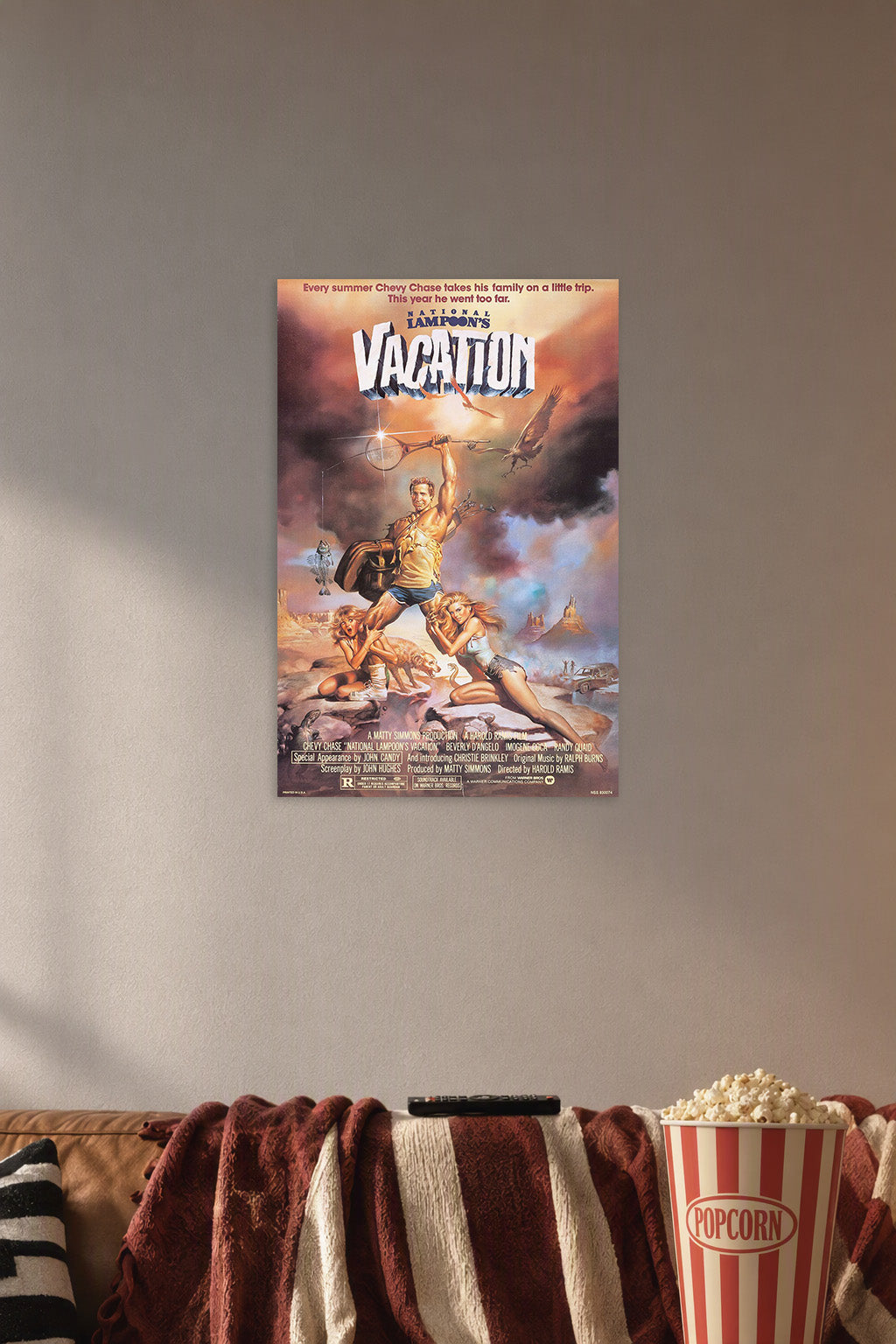 National Lampoon's Vacation Movie Poster in a cozy movie room above a brown sofa with popcorn.