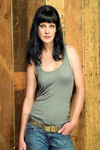 Pauley Perrette poster portrait featuring a woman with black bangs in a gray tank top and jeans against rustic wood panels.