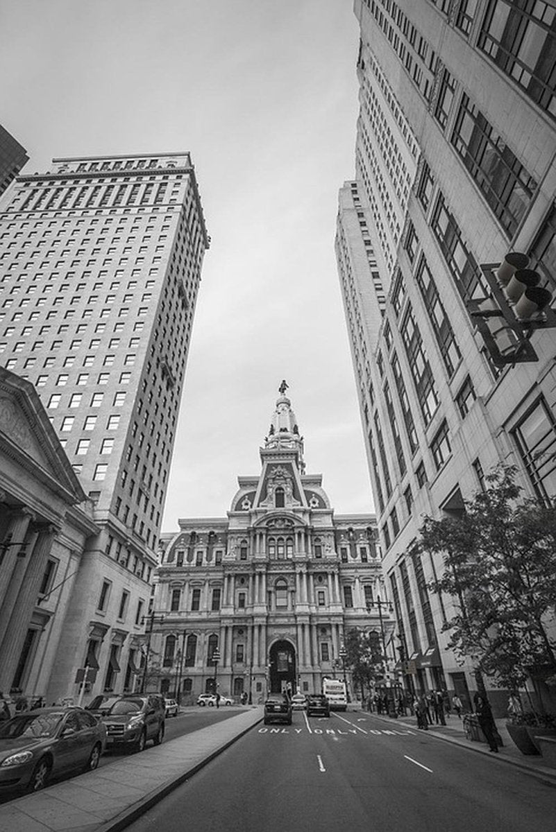 Philadelphia City Hall wall art print in black and white, with its ornate tower centered between tall downtown buildings and a street of cars.