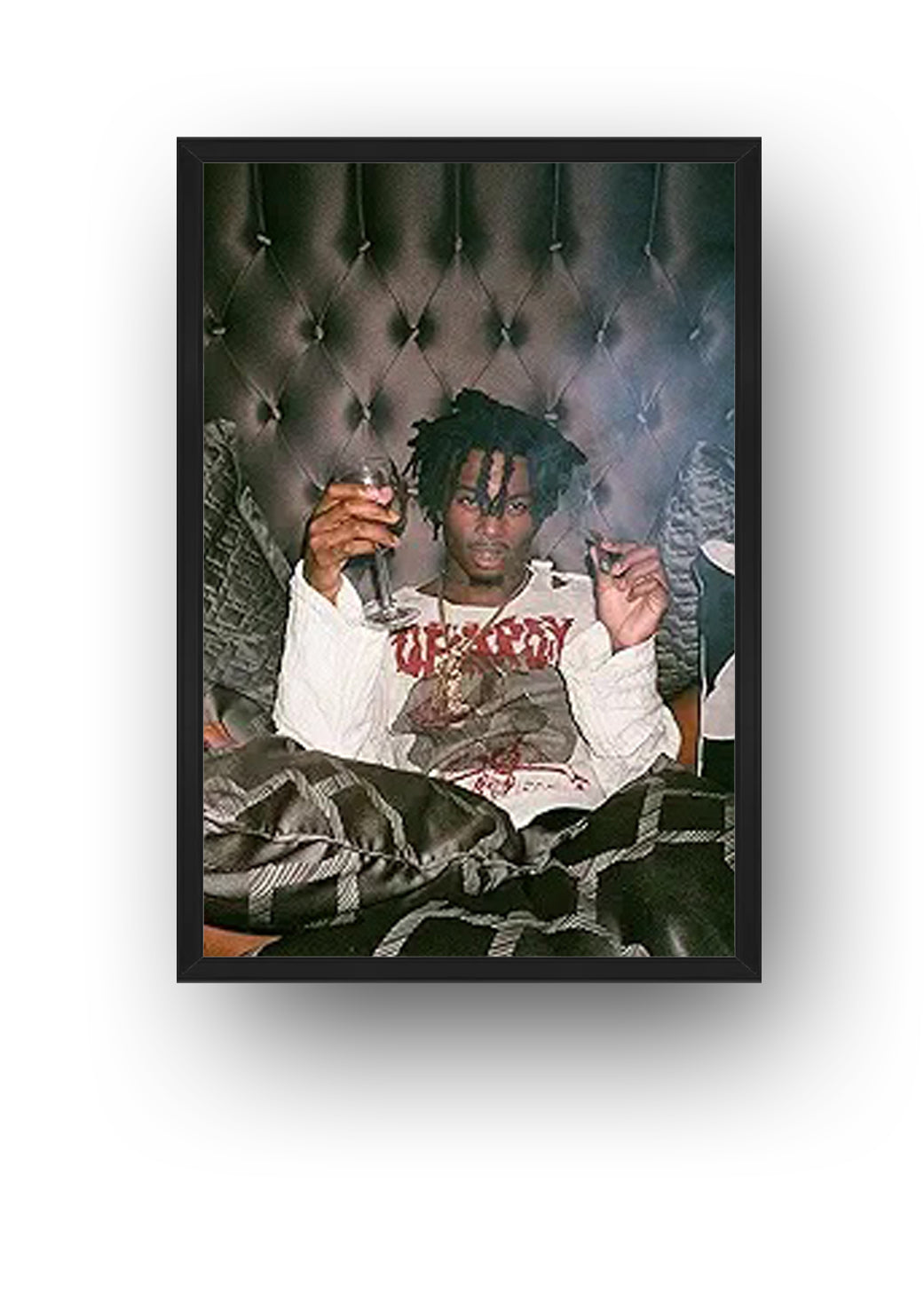 Playboi Carti framed wall art print featuring the rapper seated with a wine glass before a dark tufted background.
