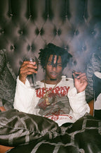 Playboi Carti poster featuring the rapper seated against a tufted backdrop, holding a wine glass and small object.