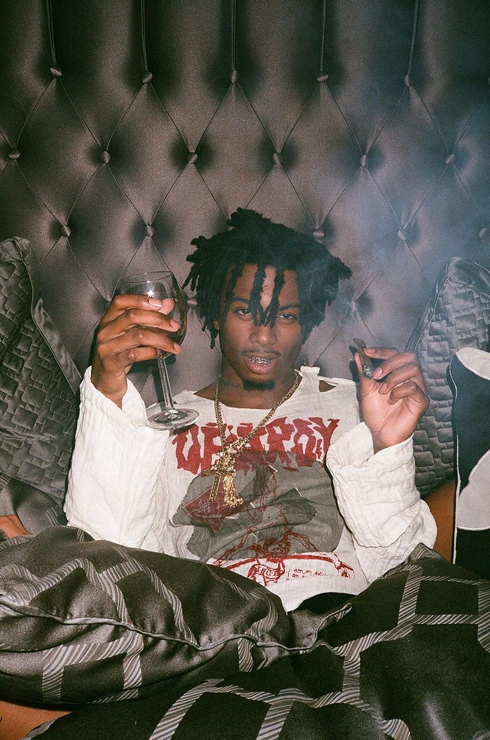 Playboi Carti poster featuring the rapper seated against a tufted backdrop, holding a wine glass and small object.