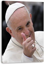 Pope Francis canvas wall art print displays the smiling pontiff in white robes and skullcap giving a thumbs-up against a dark background.