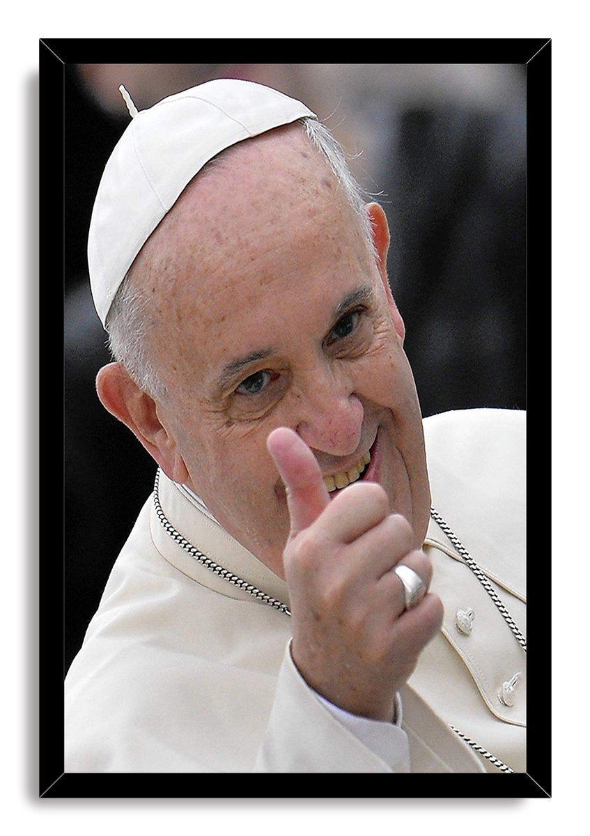 Pope Francis framed wall art print portrays the smiling pontiff in white papal attire giving a thumbs-up, set in a black frame.