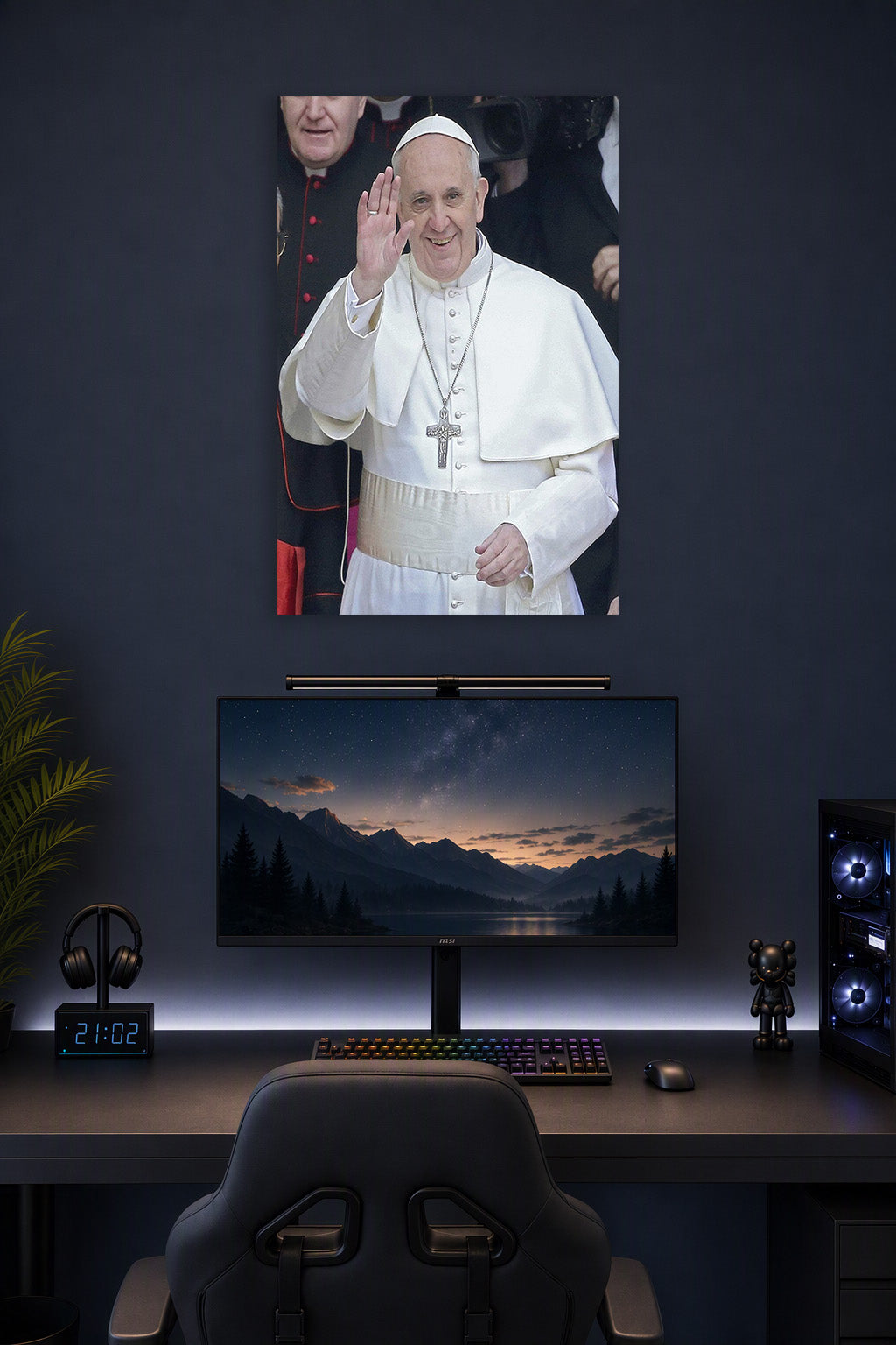 Pope Francis in a gaming desk setup above a monitor.