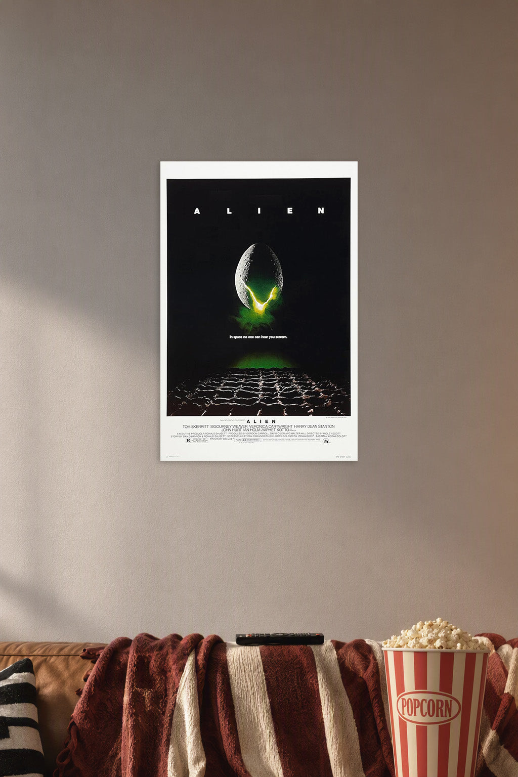 Poster Alien (1979) Movie in a cozy movie room above a brown sofa with popcorn.