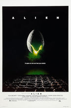Alien movie poster paper print with a cracked egg glowing green above dark ridged terrain on a black background.