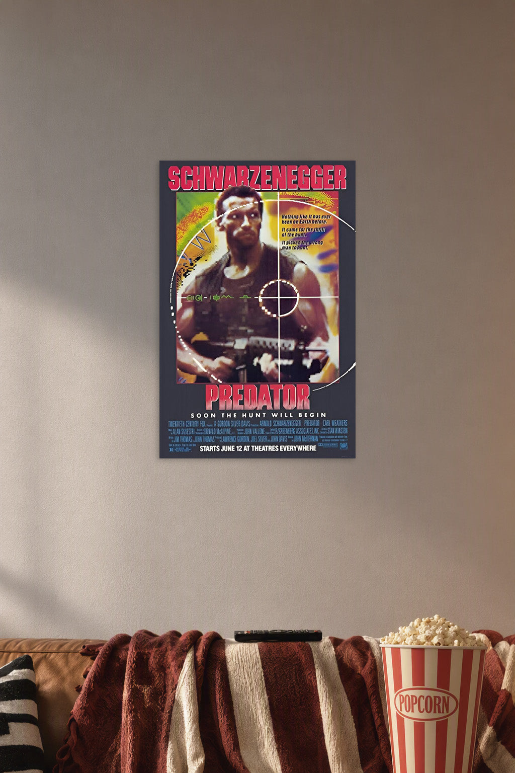 Predator (1987) Movie Poster in a cozy movie room above a brown sofa with popcorn.