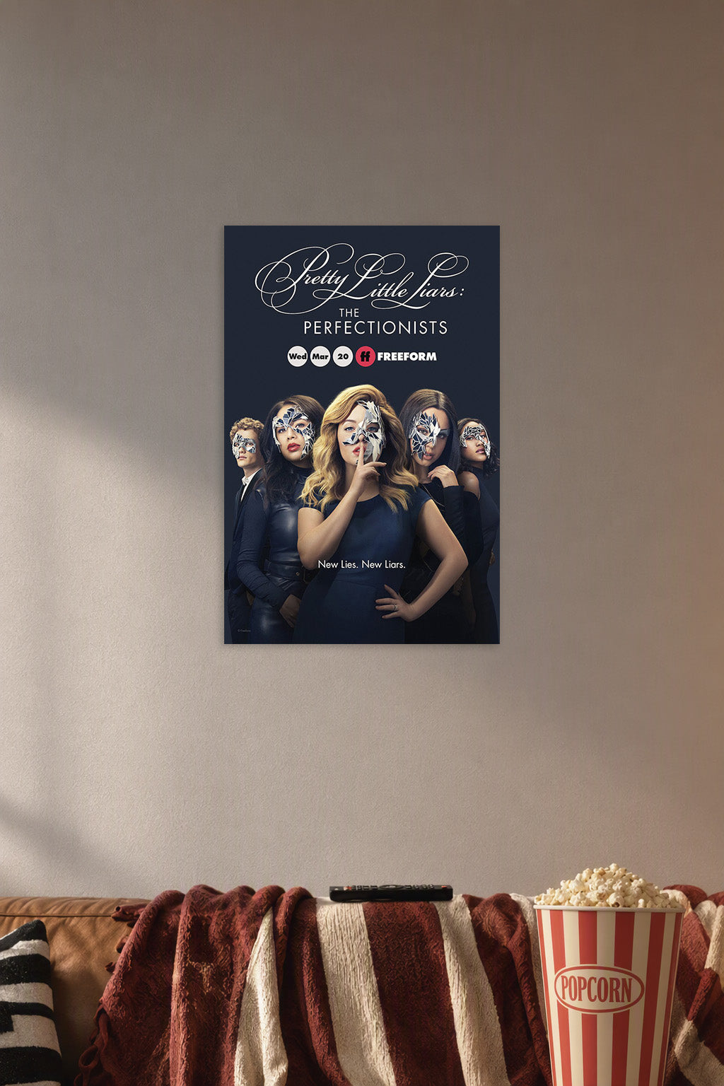 Pretty Little Liars: The Perfectionists in a cozy movie room above a brown sofa with popcorn.