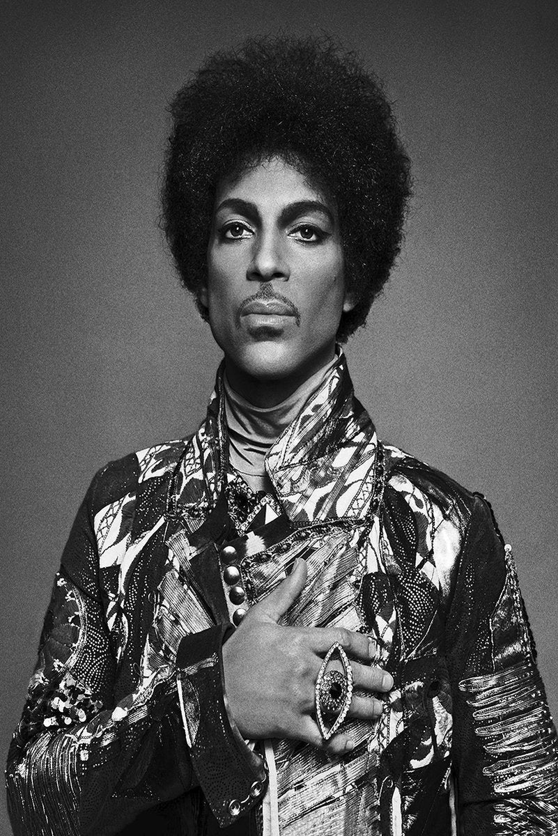 Prince poster features a black-and-white portrait of the musician with an afro, patterned jacket, and ornate ring.