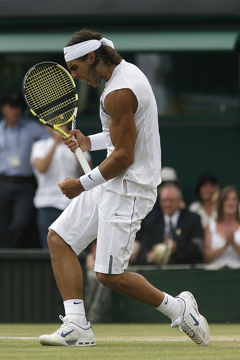 Rafael Nadal tennis wall art print captures him leaping on a grass court, gripping a yellow racket in white kit.