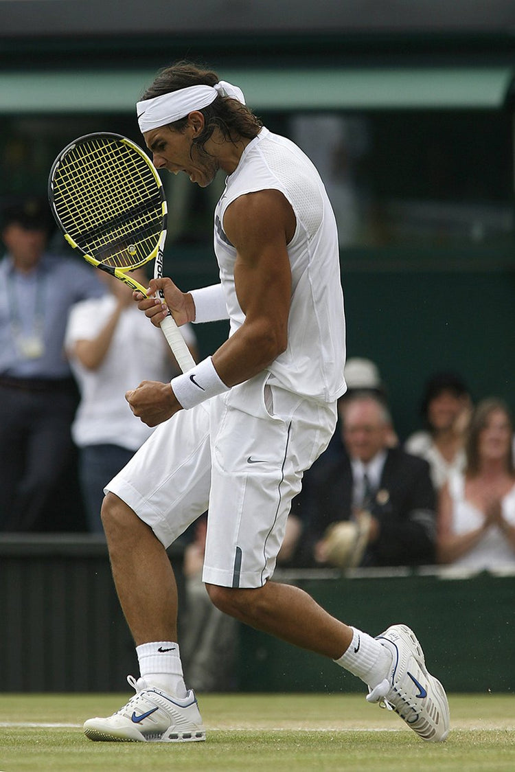 Rafael Nadal tennis wall art print captures him leaping on a grass court, gripping a yellow racket in white kit.