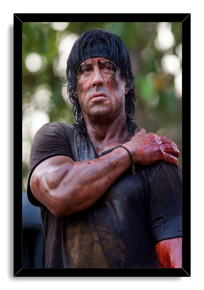 Rambo framed wall art print featuring Sylvester Stallone with a wounded arm and intense gaze, set in a black mitered frame.