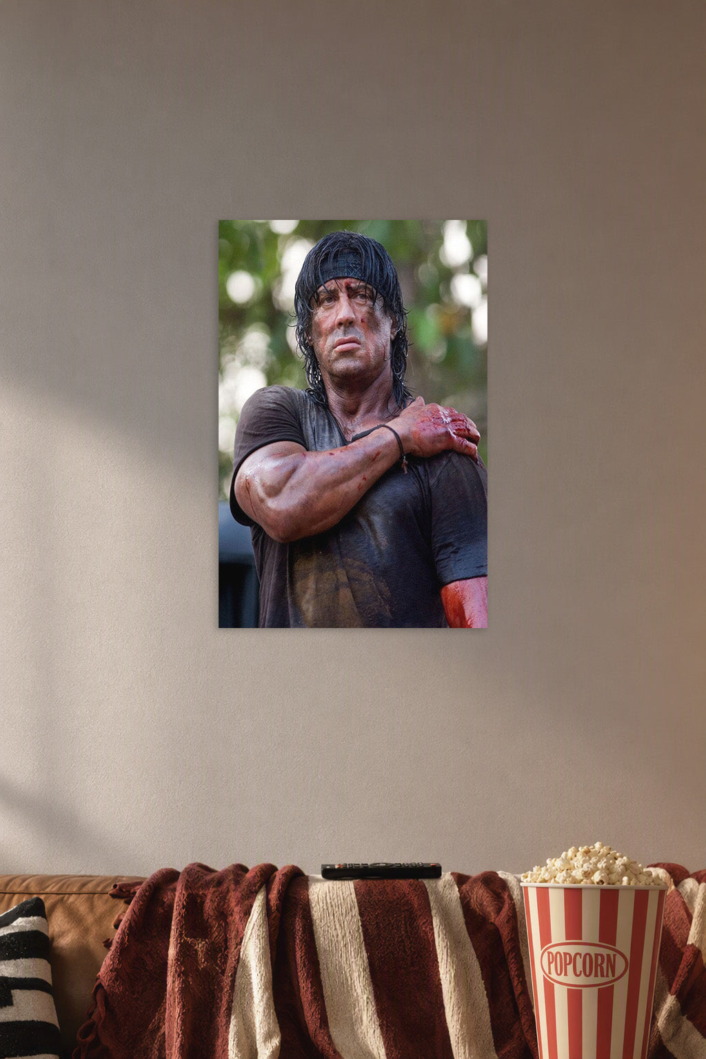 Rambo Sylvester Stallone in a cozy movie room above a brown sofa with popcorn.