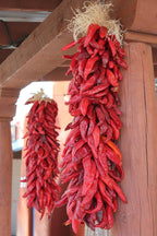 Red chili ristras wall art print featuring two bundles of dried red peppers hanging from rustic wooden beams.