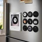 Retro mini vinyl record music player mounted on a refrigerator beside nine black Deftones-themed magnetic discs.