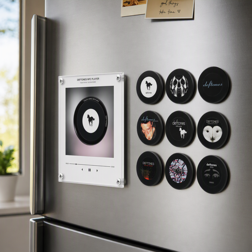 Retro mini vinyl record music player mounted on a refrigerator beside nine black Deftones-themed magnetic discs.