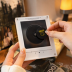 Retro mini vinyl record music player held in both hands as a Nirvana smiley-face magnetic disc is placed on its center.
