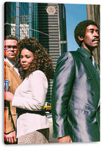 Canvas wall art print featuring three pedestrians in tailored outfits on a city street lined with tall glass buildings.