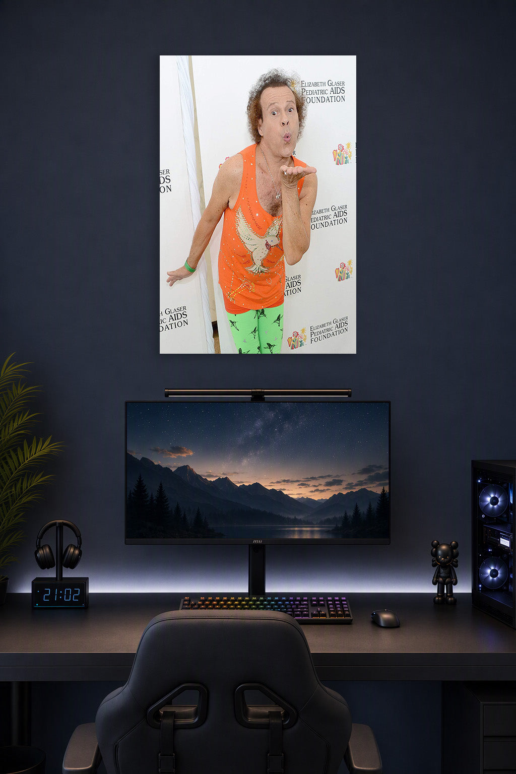 Richard Simmons in a gaming desk setup above a monitor.