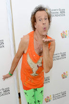Richard Simmons poster features him blowing a kiss in an orange embellished tank top and green bird-print leggings.