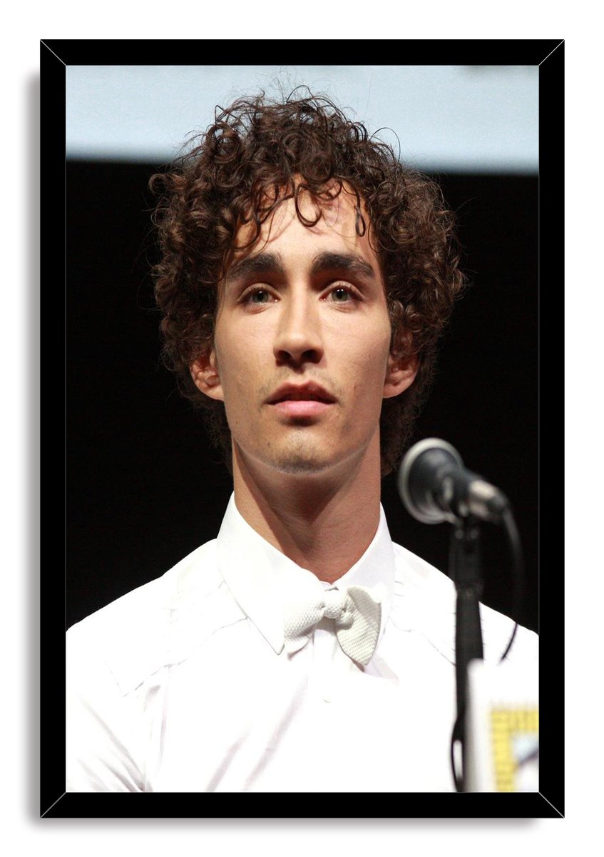 Robert Sheehan framed wall art print with curly hair, white bow tie, and microphone against a black stage backdrop.