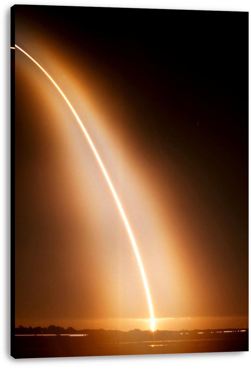 Rocket launch canvas wall art print displays a curved golden light trail over a dark silhouetted landscape, with visible wrapped edges.