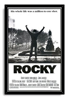 Rocky framed wall art print in a black frame, featuring a triumphant raised-fist silhouette, monument backdrop, and bold black ROCKY title.