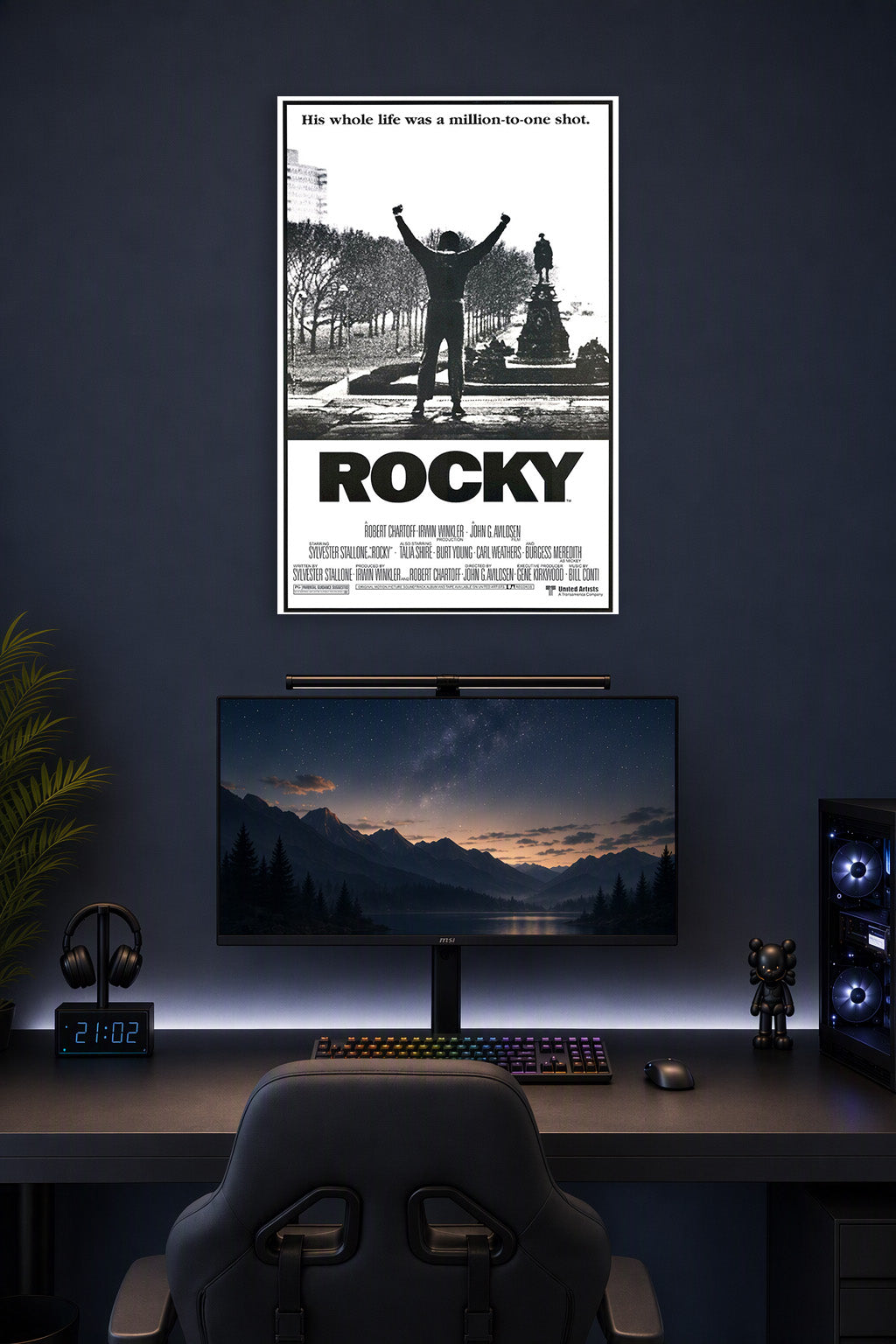 Rocky Balboa Triumphant in a gaming desk setup above a monitor.