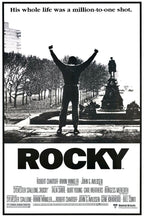 Rocky wall art print in black and white, with a lone man raising both fists before trees and a monument, above bold ROCKY title text.